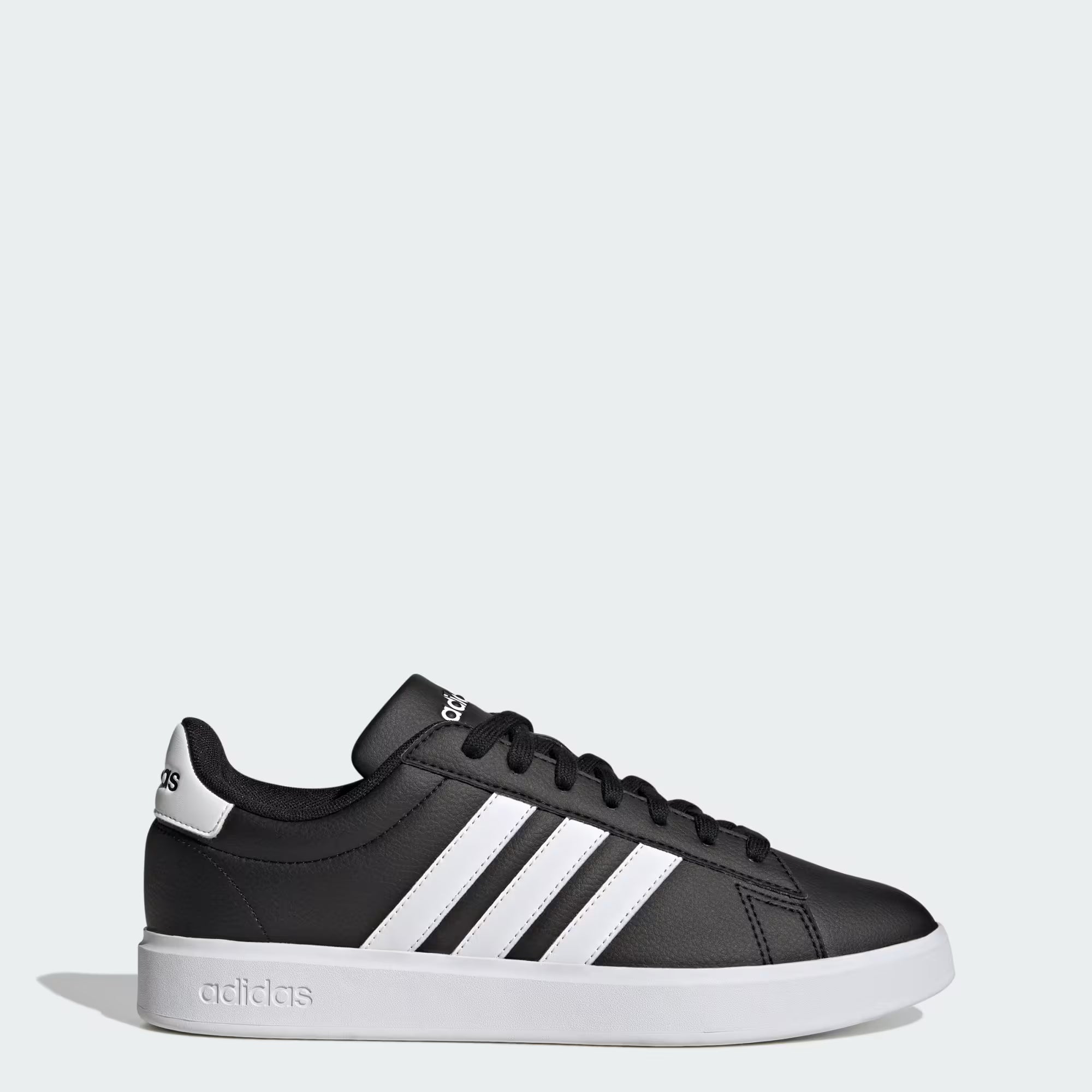 The adidas Grand Court 2.0 - Men in Core Black/Cloud White features classic white stripes, a white sole, and Cloudfoam Comfort cushioning. Side view on a light gray background shows the adidas logo on the heel and tongue.