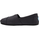 The TOMS Classic Canvas - Men in Black on Black is a slip-on shoe with a flat sole, shown from the side on a white background. Inspired by classic TOMS, it delivers effortless style and comfort in a timeless design.