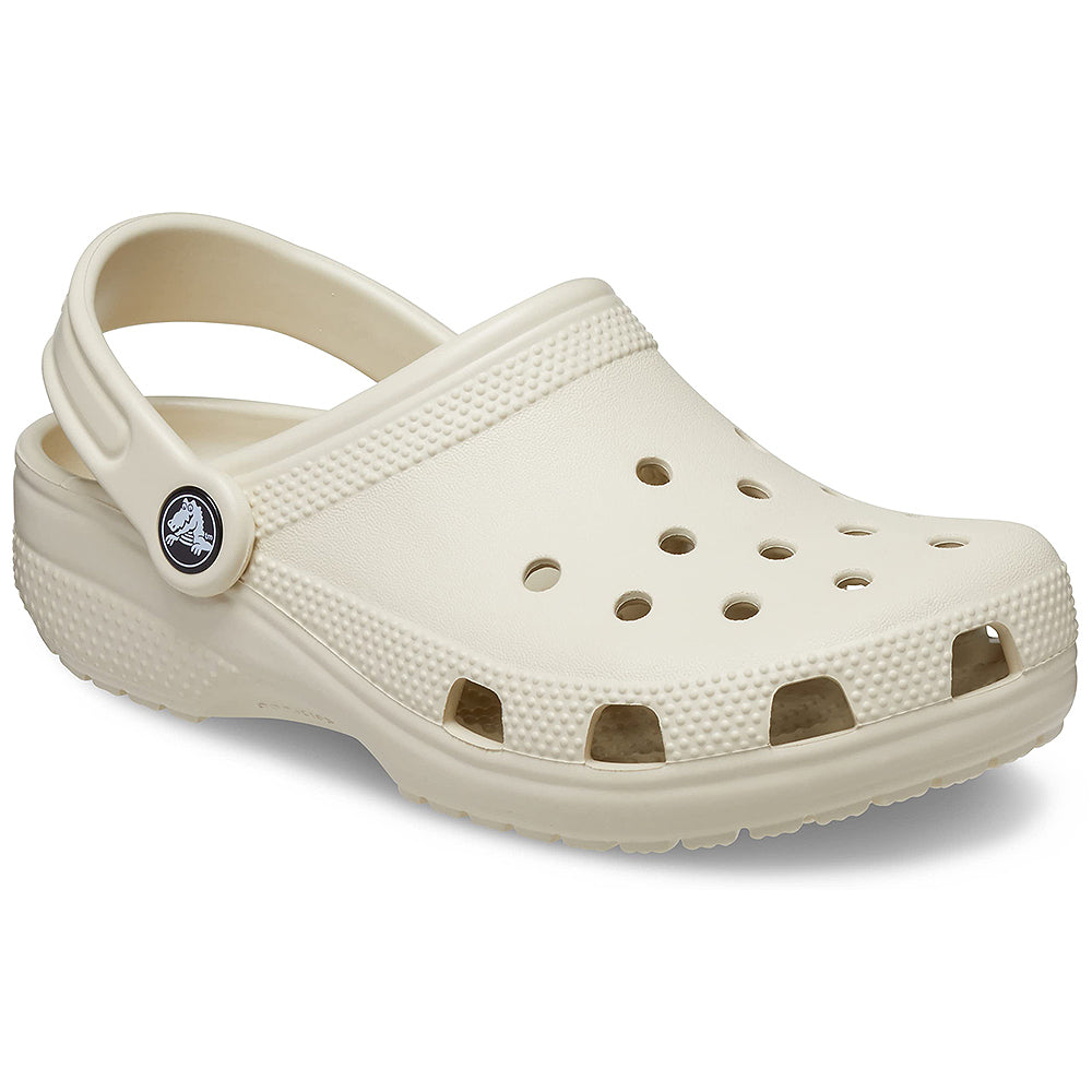 The Crocs Classic Clog - Kids in Bone features a textured sole, ventilation holes on top and sides, and an adjustable heel strap with the Crocs logo.