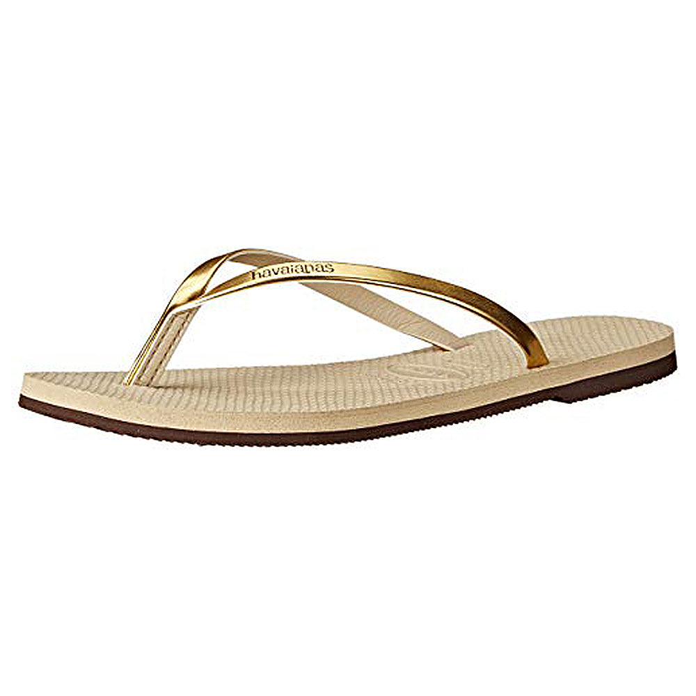 The Havaianas Slim Metalic - Womens sandal in Sand Grey/Light Gold features metallic gold straps and a textured sole, styled after classic Havaianas and shown against a white background.