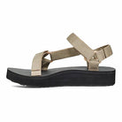 The Teva Midform Universal - Womens sandal in Metallic Champagne features universal straps and a thick black sole, shown in side profile on a white background. This water-ready sandal combines comfort and style for outdoor adventures.