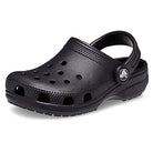 The Crocs Classic Clog - Kids in black features ventilation holes, a textured sole, and an adjustable heel strap with the Crocs logo—perfect for everyday comfort.