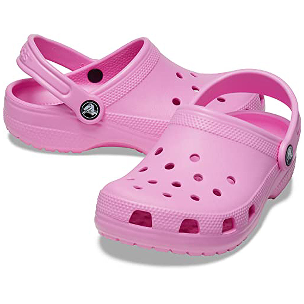 A pair of Crocs Classic Clog - Kids in Taffy Pink, featuring ventilation holes, adjustable heel straps, and textured soles, are positioned side by side on a white background.