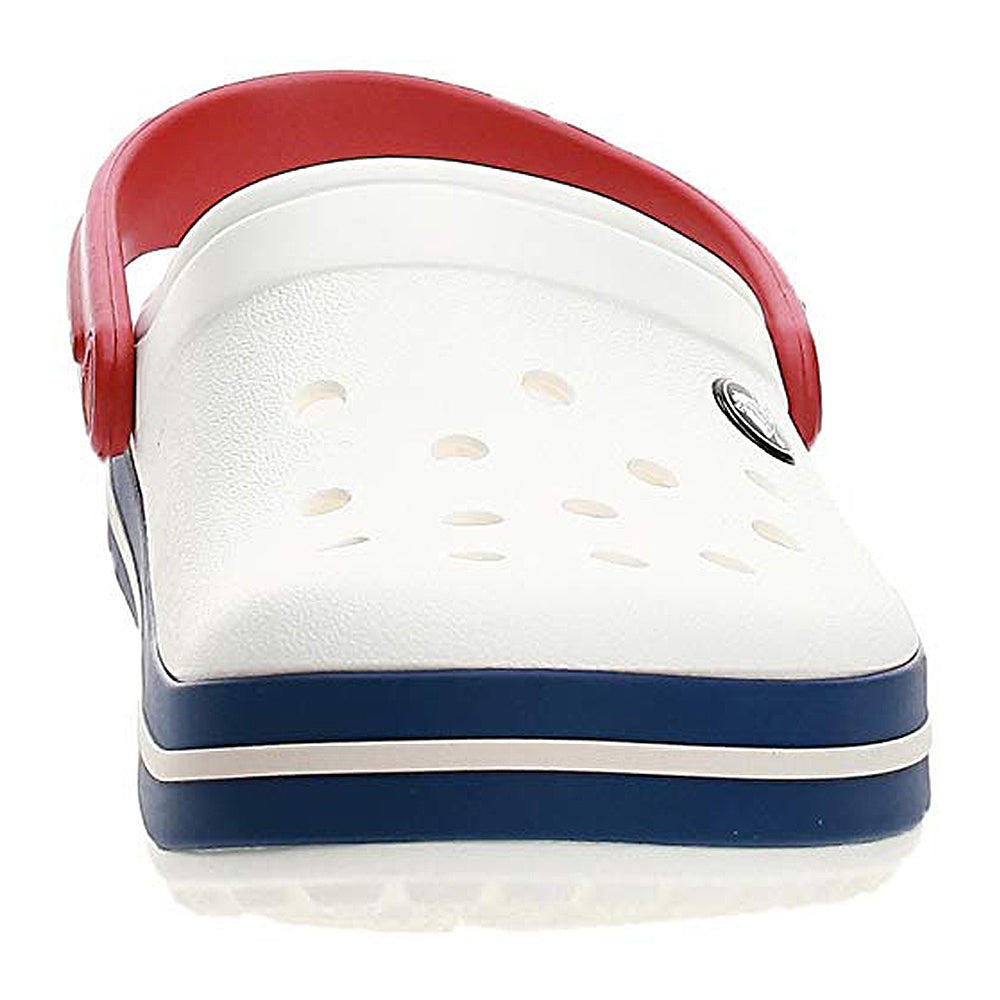 The Crocs Crocband Clog Seasonal Colors - Unisex is shown front view in white with a red strap and navy stripe on the sole, ventilation holes on top, and a circular logo on the side.