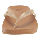 A front view of the Reef Cushion Spring Joy - Womens sandal in tan, featuring a metallic beige thong strap and a flat, textured cushion footbed—ideal for women seeking stylish and comfortable flip flops.