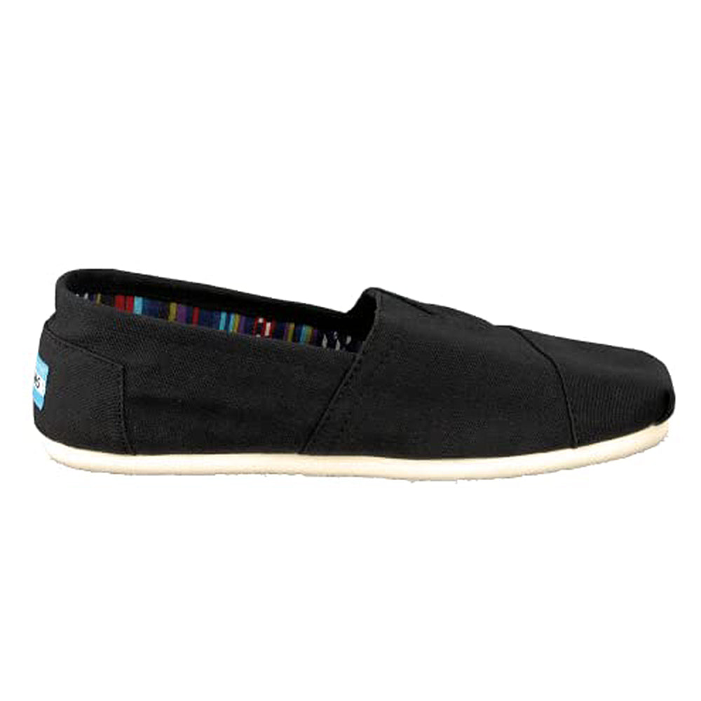 The TOMS Classic Canvas - Men is a black slip-on shoe with a white sole and multicolored striped inner lining, shown from the side.