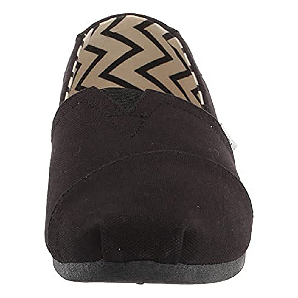 Front view of the TOMS Alpargata - Womens slip-on in black, featuring recycled cotton canvas and a beige and black zigzag inner lining. This shoe has a simple, rounded toe and a flat sole.