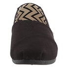 Front view of the TOMS Alpargata - Womens slip-on in black, featuring recycled cotton canvas and a beige and black zigzag inner lining. This shoe has a simple, rounded toe and a flat sole.