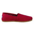 The TOMS Alpargata ESP - Women is a red canvas slip-on with a brown rubber sole, shown from the side. It has a striped inner lining and a blue and white heel label for classic style.