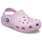 The Crocs Classic Clog - Kids in light pink features ventilation holes, a textured sole, and a pivoting heel strap, shown against a white background.