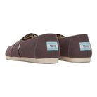 A pair of brown canvas Alpargata - Womens slip-ons by TOMS, shown from the back and side, with white soles and a light blue TOMS logo patch on the heel; part of the earthwise collection made with recycled cotton.