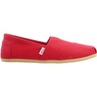 The TOMS Classic Canvas - Men is a red slip-on shoe with a beige rubber sole, white TOMS tag on the side, and blue heel patch.