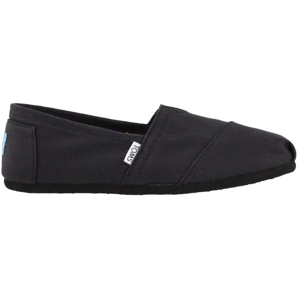 The TOMS Classic Canvas - Men is a black slip-on shoe with a low profile, flat sole, minimalist design, visible stitching, and a small white TOMS label on the side, showcasing the classic style of the brand.