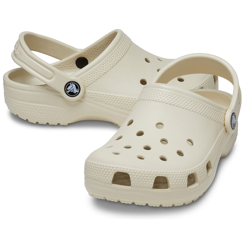 A pair of beige Crocs Classic Clog - Kids shoes with ventilation holes and adjustable heel straps, shown on a white background.