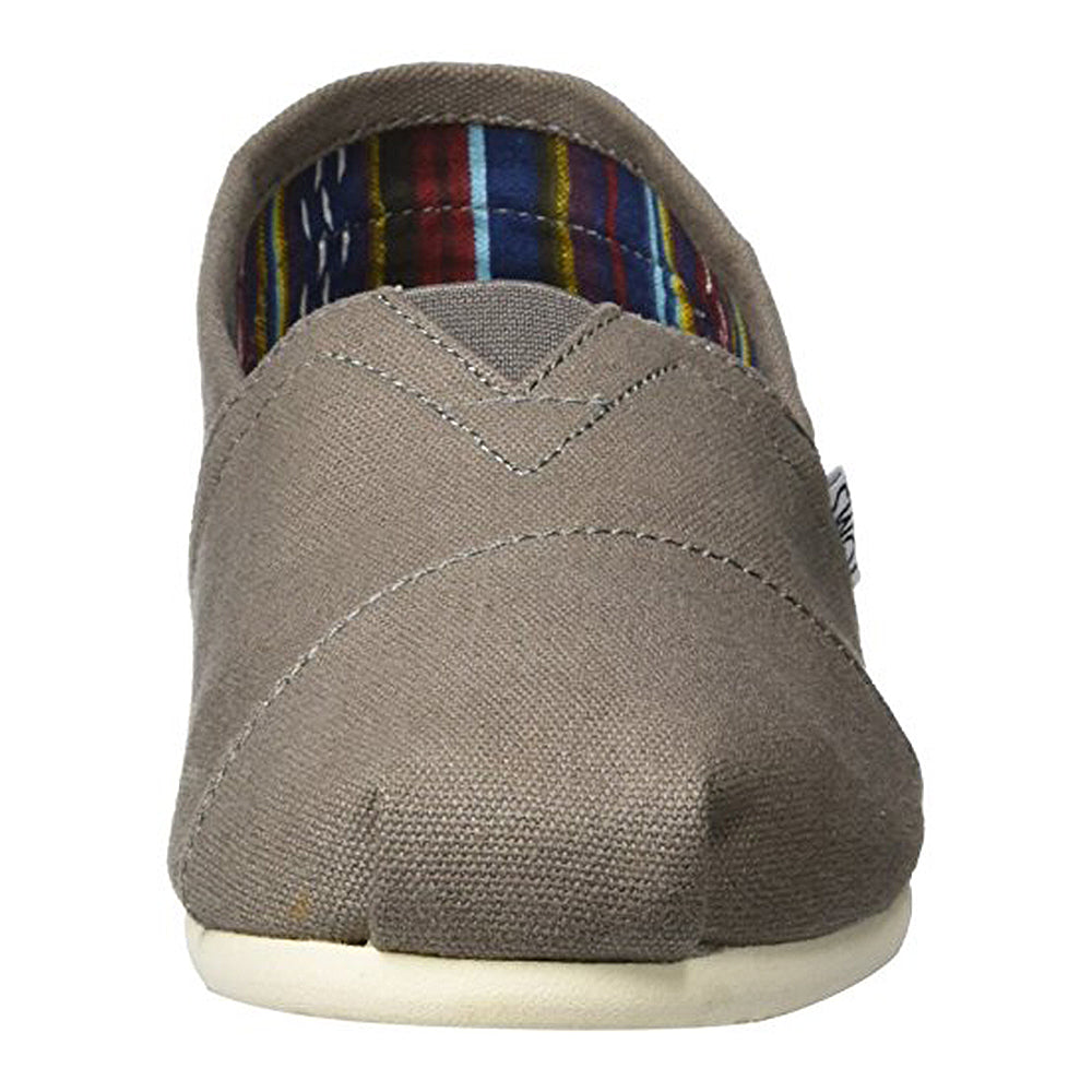 A front view of the TOMS Classic Canvas - Men slip-on in light brown, featuring visible stitching, a white rubber sole, and a colorful striped fabric lining.