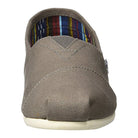 A front view of the TOMS Classic Canvas - Men slip-on in light brown, featuring visible stitching, a white rubber sole, and a colorful striped fabric lining.