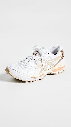 The ASICS Gel-Kayano 14 - Womens features a white athletic design with light beige accents, mesh details, and a textured sole. Loosely laced and angled on a white background, it includes GEL Technology for comfort.