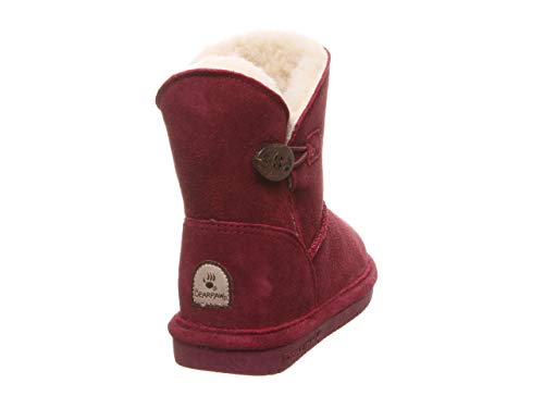 The BEARPAW Rosie Youth Boots feature red suede, a soft white fleece lining, sheepskin footbed, decorative side button, rubber sole, and a Bearpaw logo patch near the heel, shown from a rear side angle.
