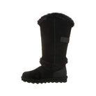 A single BEARPAW Sheilah Boot for women in black suede with faux fur trim at the top and ankle, a flat rubber sole, and a decorative side strap. The boot is shown in profile against a white background.