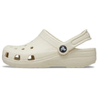 A side-view of the Crocs Classic Clog - Kids in beige, featuring ventilation holes and an adjustable heel strap, shown on a white background.