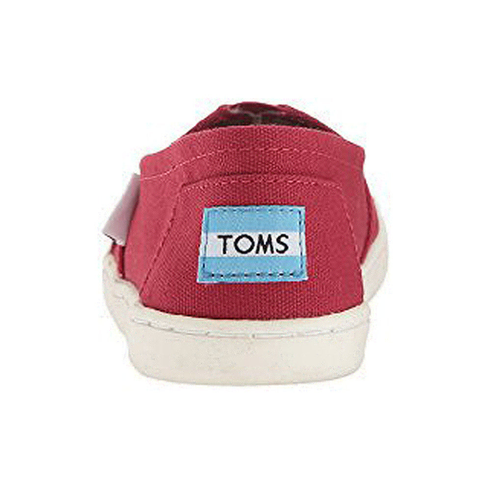 A red canvas TOMS Alpargata ESP - Women shoe with a white rubber sole, shown from the back. The heel displays a blue and white TOMS label, reflecting the brands buy one give one promise.