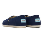 A pair of navy blue TOMS Alpargata - Womens slip-on canvas shoes with white soles, shown from the back and side. Each heel features a blue and white TOMS label; part of the earthwise collection with recycled cotton uppers.