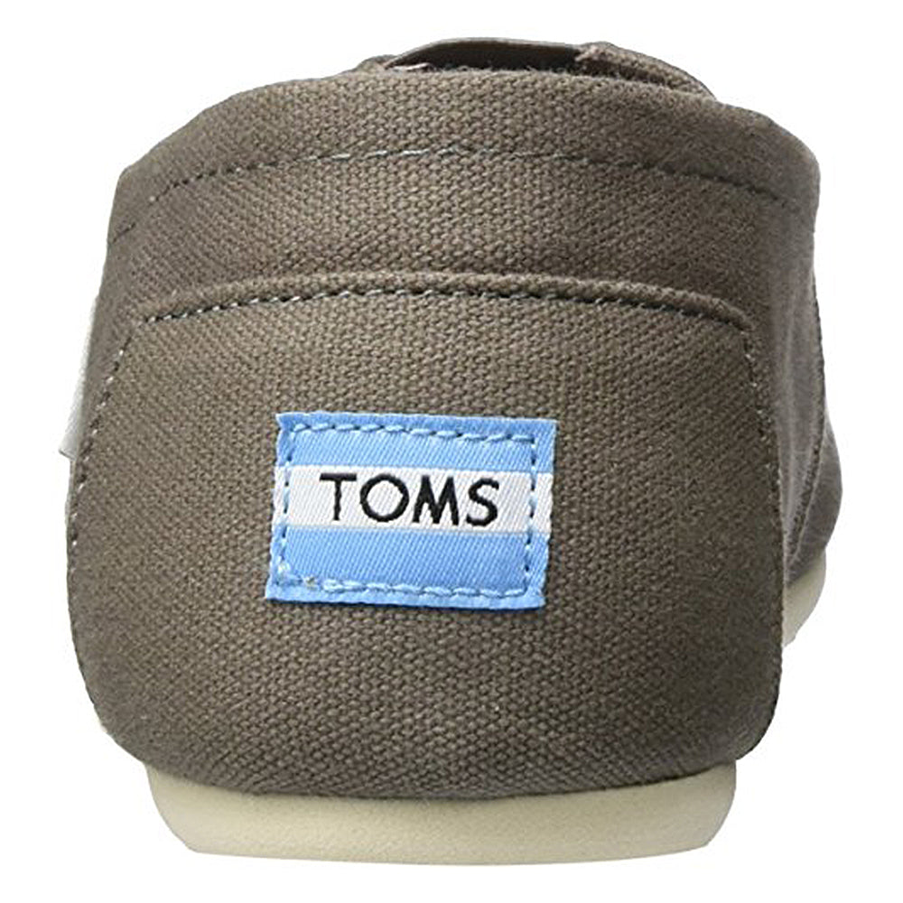 A close-up of the heel of a TOMS Classic Canvas - Men slip-on shows a blue and white TOMS label on brown canvas, with a white sole and minimalist style.
