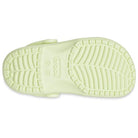 The image shows the sole of a light yellow Crocs Classic Clog - Kids shoe, featuring a textured tread pattern and the Crocs logo centered on the bottom.