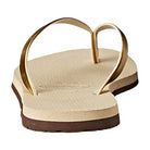 A close-up of the Havaianas Slim Metalic - Womens sandal in beige, featuring gold straps and a textured sole, photographed from heel to toe.