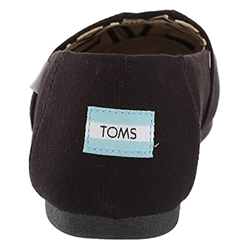 A rear view of the TOMS Alpargata - Womens black canvas slip-on with a light blue and white rectangular TOMS logo label stitched on the heel from the earthwise collection.