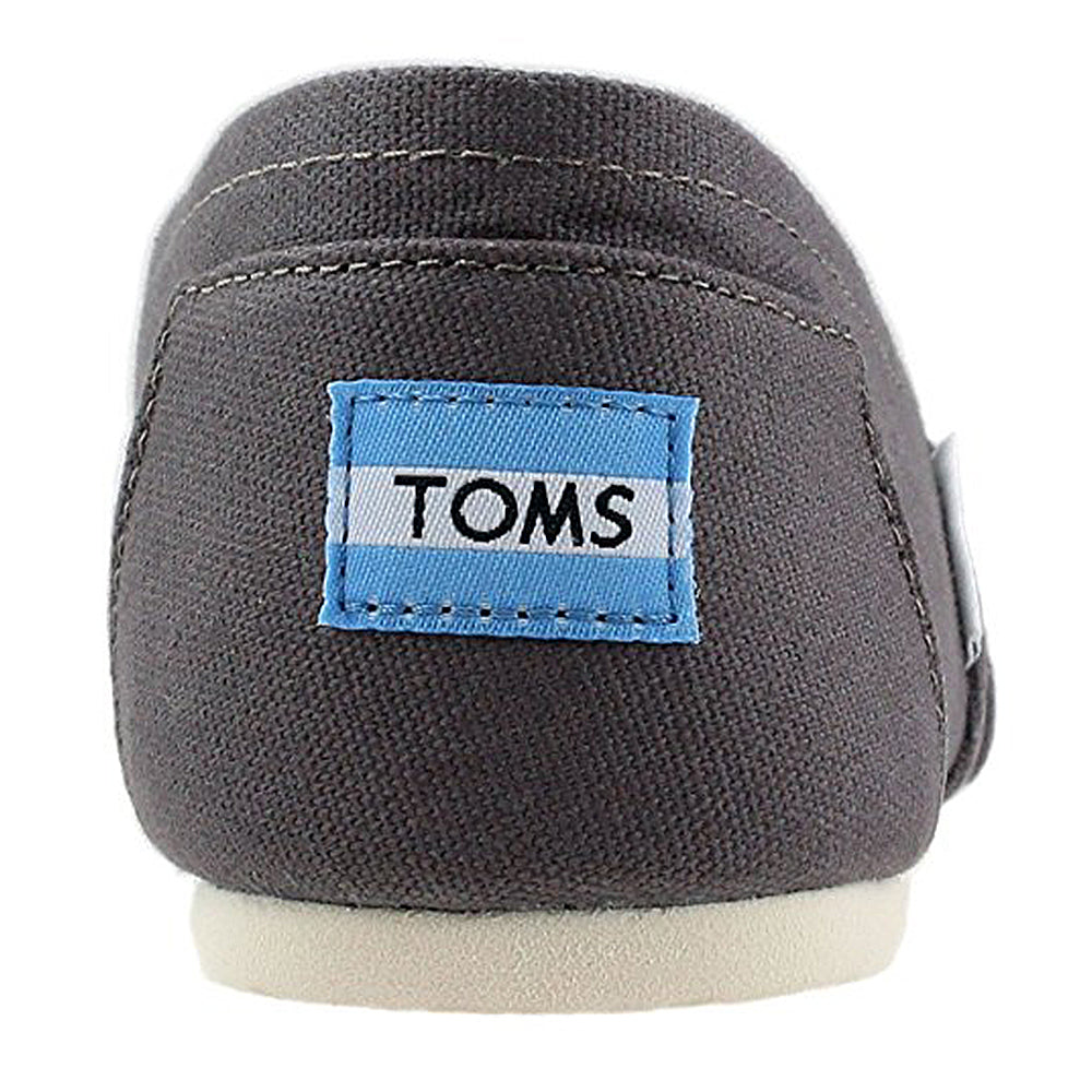 Close-up of the back of a gray TOMS Alpargata ESP - Women shoe, featuring a blue and white TOMS label on the heel, an off-white sole, and the classic slip-on style that reflects TOMS’ signature buy one give one spirit.