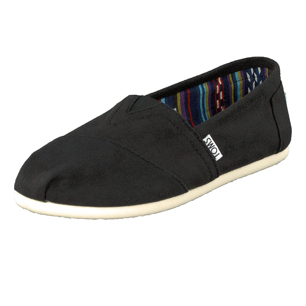 The TOMS Classic Canvas - Men is a black slip-on shoe with a light sole, colorful striped inner lining, and a small TOMS label on the side.