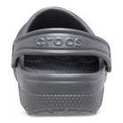 A close-up rear view shows a single gray Crocs Classic Clog - Kids with the heel strap up. The Crocs logo is embossed on the strap, and textured details appear on the heel and sole.