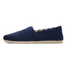 The Alpargata ESP - Women by TOMS is a navy blue slip-on canvas shoe with a beige rubber sole and slightly pointed toe—ideal for comfort lovers and fans of the TOMS buy one give one spirit.