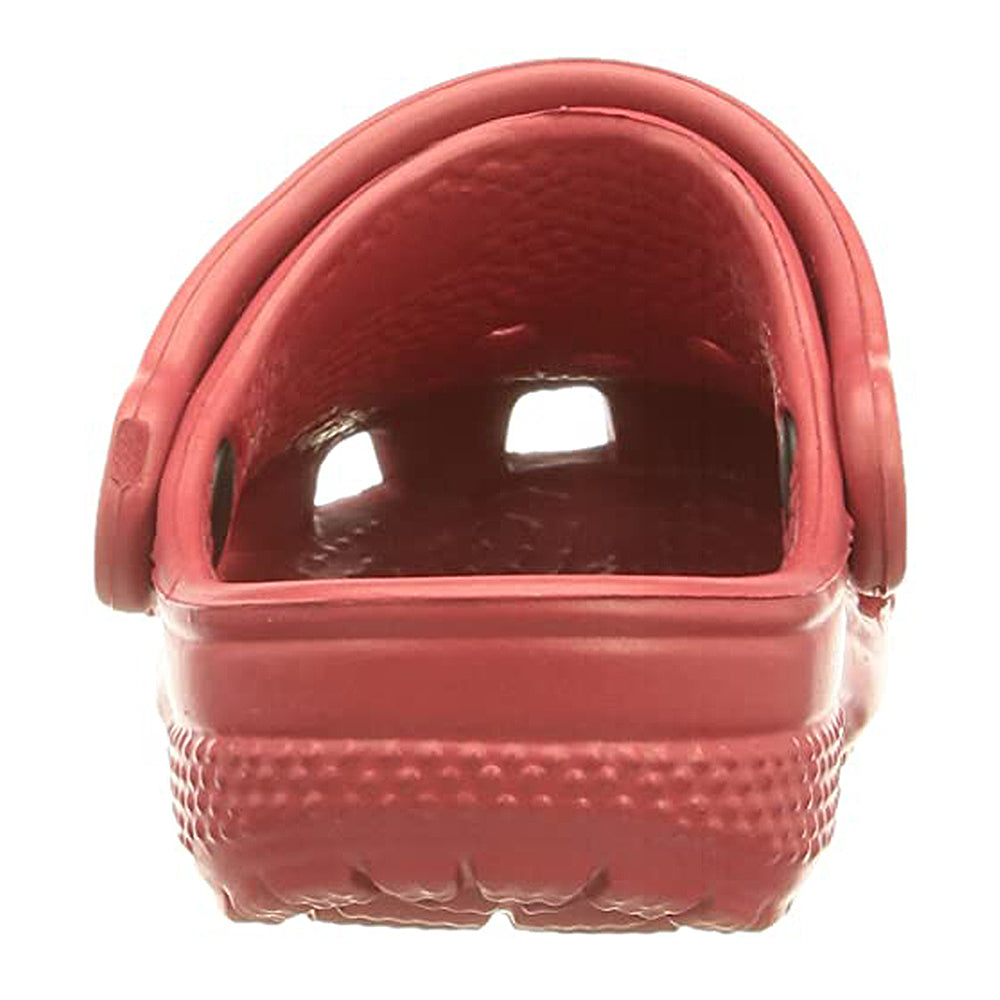 A close-up rear view of a single red Crocs Classic Clog for kids shows its textured sole and two visible side ventilation holes.