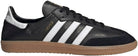 The adidas Samba Decon Shoes - Men in Core Black/Cloud White/Core Black feature a black leather upper, white stripes and heel tab, gold SAMBA text, and a light brown gum sole, shown from the side on a white background.