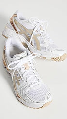 A pair of ASICS Gel-Kayano 14 - Womens sneakers in white with beige and tan accents, white laces, mesh panels, and GEL Technology cushioning, displayed on a white background.