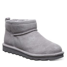 The BEARPAW Shorty Boots - Womens is shown in gray suede with a flat textured rubber sole, rounded toe, and plush lining, captured from a side angle on a white background—ideal for cozy all-day comfort.