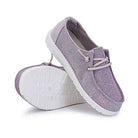 A pair of light purple Hey Dude Wendy Youth - Girls shoes with white textured soles and laces, shown with one standing upright and the other on its side to highlight the sole—ideal lightweight comfort for everyday wear.