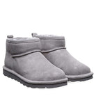 The BEARPAW Shorty Boots for women feature light gray suede, a rounded toe, visible stitching, plush shearling lining, flat ridged soles, and a back pull tab.
