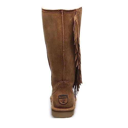 The BEARPAW Tamara Boots for women are tan, knee-high suede boots with decorative fringe on one side and a brand logo patch near the heel, viewed from the back.