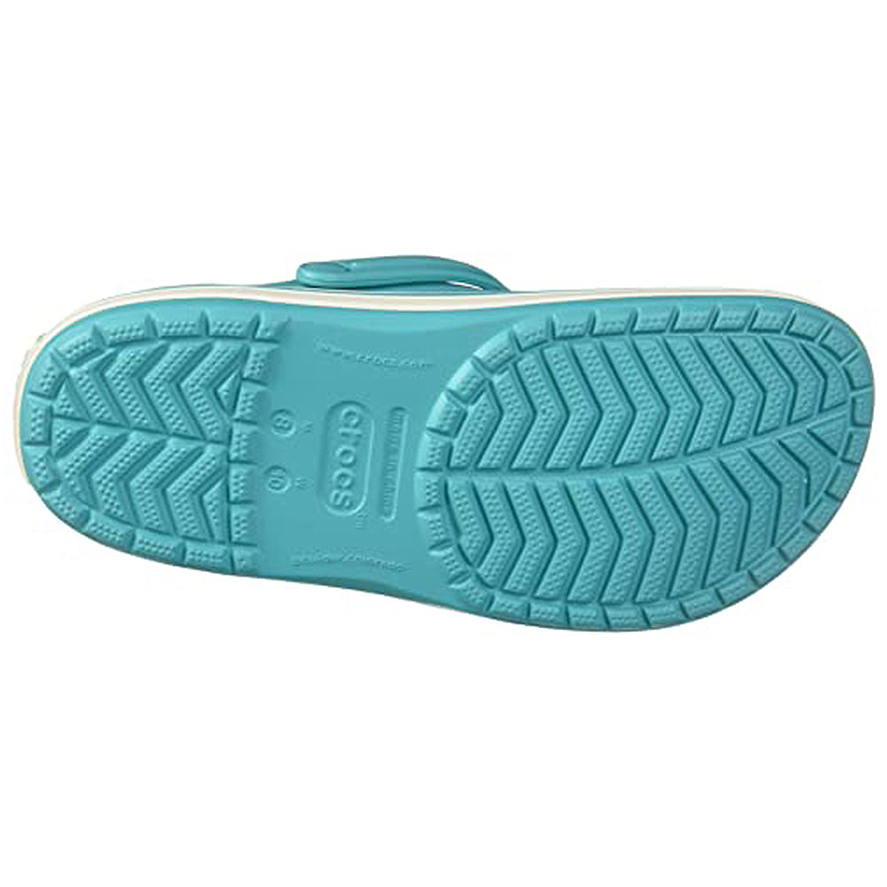 The image shows the bottom view of a light blue Crocs Crocband Clog Seasonal Colors - Unisex, featuring a textured, non-slip zigzag sole with the Crocs logo embossed in the center. This unisex style is available for sale.