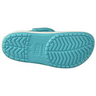 The image shows the bottom view of a light blue Crocs Crocband Clog Seasonal Colors - Unisex, featuring a textured, non-slip zigzag sole with the Crocs logo embossed in the center. This unisex style is available for sale.