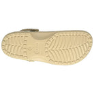 The image displays the beige sole of the Crocs Classic Camo Clog - Unisex, showcasing textured tread and a central Crocs logo. These slip-on shoes are praised for their comfort and versatility as water-friendly footwear.