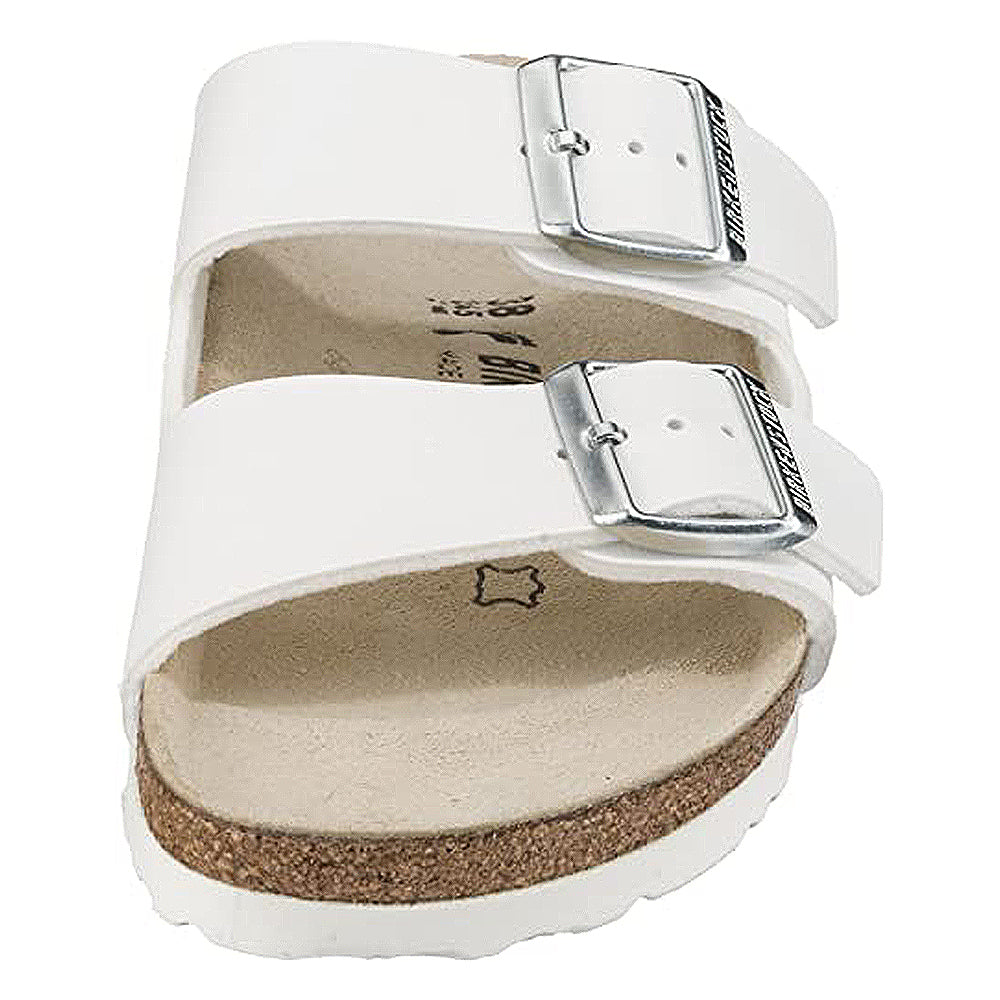 The Birkenstock Arizona - Womens sandal features two wide silver-buckled straps, a tan cork footbed for orthopedic comfort, and a white sole. Inspired by classic Birkenstock design, its shown from the front at a slight angle.