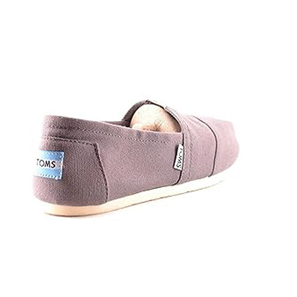 A single Classic Canvas - Men slip-on by TOMS, in gray with a beige rubber sole, is shown from the back left. The heel features a small blue TOMS logo label.