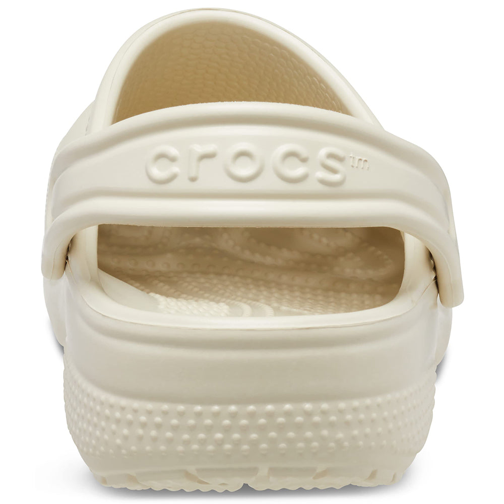 A close-up rear view of the Crocs Classic Clog - Kids in cream, featuring the back strap embossed with the CROCS logo.