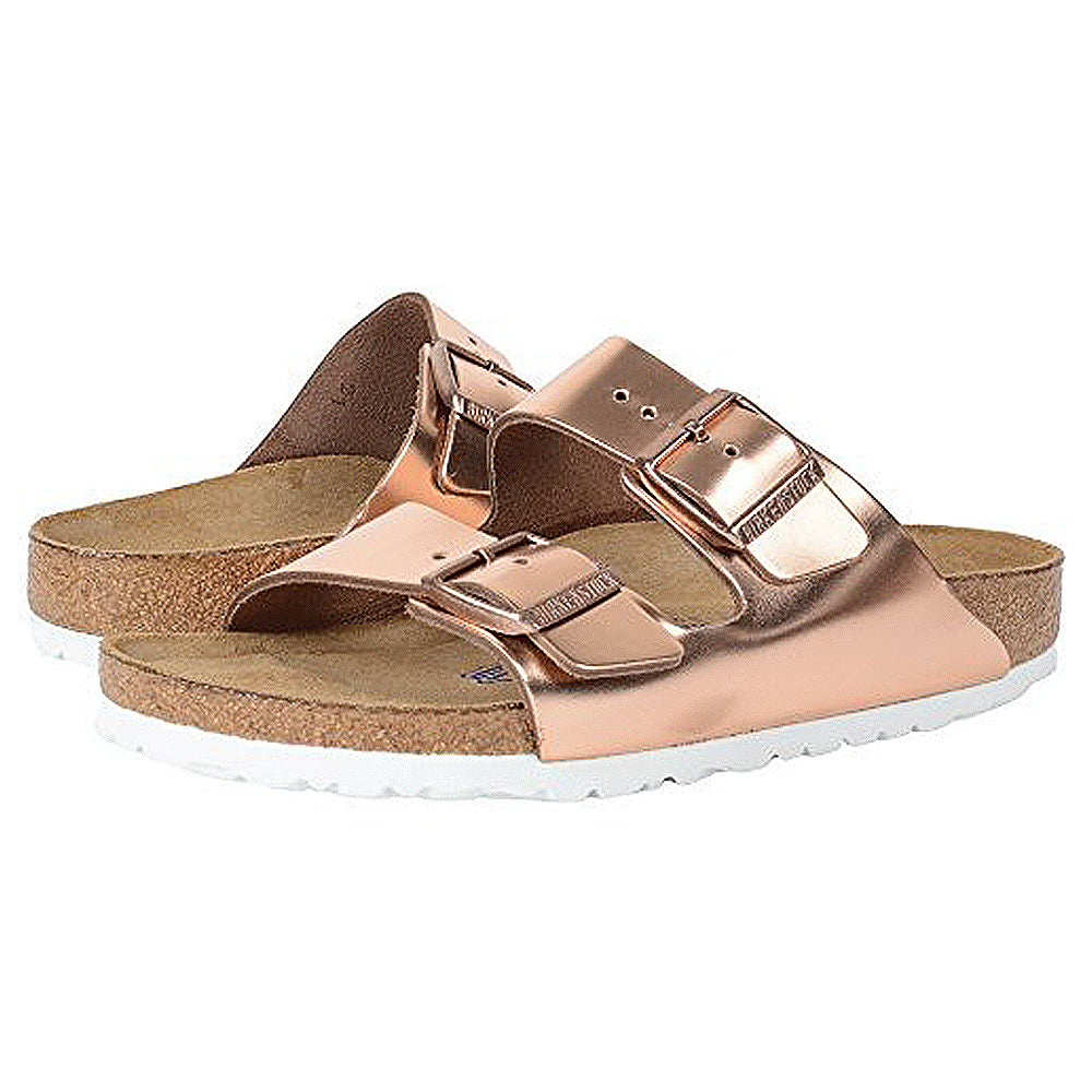 The Birkenstock Arizona - Womens sandals feature rose gold metallic double straps with adjustable buckles, a cork footbed, and white soles for orthopedic walking comfort.