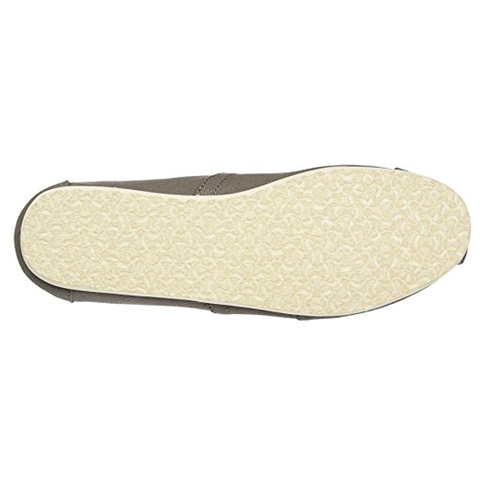 A top-down view of the TOMS Classic Canvas - Men alpargata sole displays a light beige, textured rubber surface with a subtle pattern. The slip-on shoe features a classic design in gray or taupe canvas.