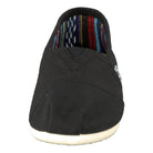 A front view of the TOMS Classic Canvas - Men shoe in black, featuring a white sole, colorful striped inner lining, and a convenient slip-on design.